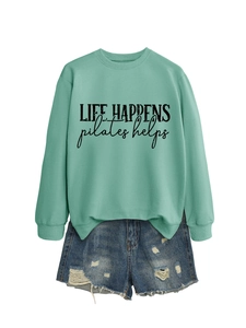 Flat lay of a mint green sweatshirt with Life Happens text and frayed denim shorts