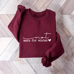 Close-up of wine red sweatshirt featuring white not made for winter text and heart