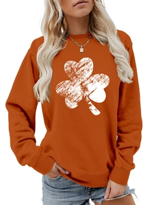 Detail of orange crewneck sweatshirt featuring a large white clover print and ribbed cuffs