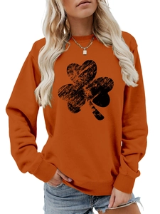 Close-up of orange crewneck sweatshirt featuring a large black distressed clover print