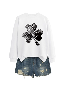 Detail of white crewneck sweatshirt with distressed clover print and frayed denim shorts