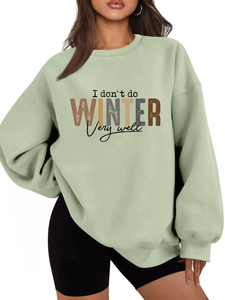 Close-up of sage green sweatshirt featuring I don't do WINTER printed graphic text