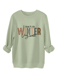 Detail of sage green sweatshirt showing printed letters and rolled cuffs on white background