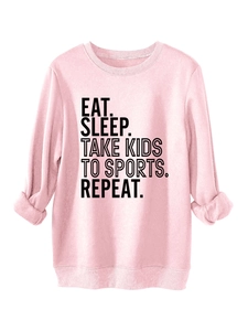 Close-up of pink crewneck sweatshirt featuring black EAT SLEEP TAKE KIDS TO SPORTS text
