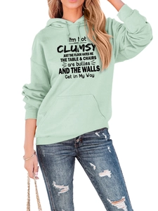 Detail of mint green loose hoodie with 'I'M NOT CLUMSY' slogan and ripped denim jeans