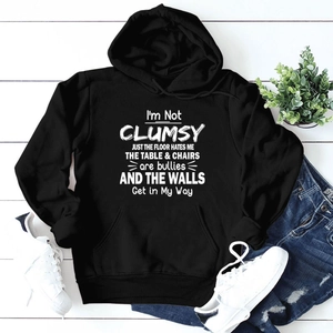 Flat lay of a black loose-fitting hoodie with white text paired with ripped blue jeans