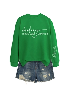 Dettaglio della felpa verde con stampa di testo bianco e pantaloncini di jeans strappati