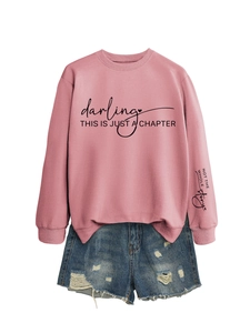 Dettaglio della felpa rosa con stampa e pantaloncini di jeans strappati in un set