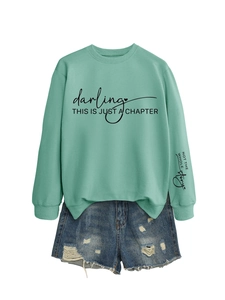 Dettaglio della felpa verde menta con stampa artistica nera e pantaloncini denim