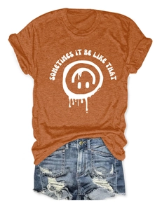 Détail du t-shirt orange caramel avec motif sourire et short en jean bleu délavé