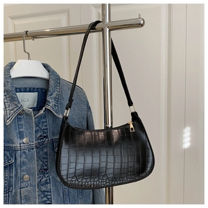 Détail de la texture crocodile noire et de la fermeture éclair dorée du sac sous le bras