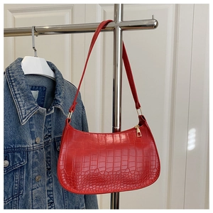 Détail du sac sous le bras en similicuir rouge vif avec texture gaufrée crocodile