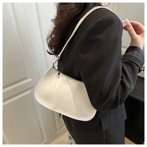 Détail d'un sac sous le bras blanc en simili cuir gaufré crocodile porté par un mannequin