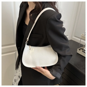 Sac baguette blanc à motif crocodile porté avec un blazer noir pour un look tendance