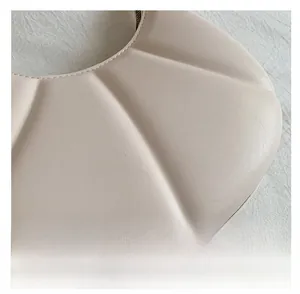 Detail of off-white leather handbag with unique shell-shaped stitching and matte texture