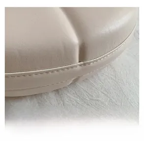 Close-up of precise double stitching and premium leather texture on a beige handbag