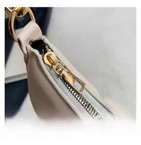 Detail of smooth gold zipper hardware on premium beige leather crossbody bag