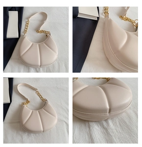 Detail view of cream crescent bag featuring shell-style quilting and gold chain strap