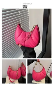 Detailed close-up of a rose red pleated crescent handbag with a gold chunky metal chain