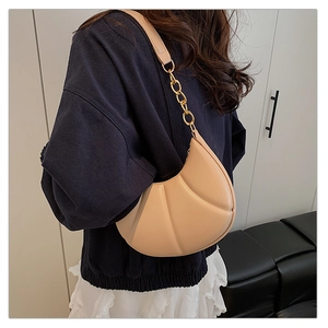 Detail of a chic cream crescent bag with quilted pattern and gold chain strap detail