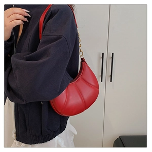 Detail of red quilted leather underarm bag with gold chain and zip closure