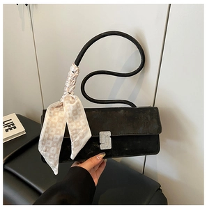 Detail of black suede baguette bag with wavy handle, silk scarf and diamond-set silver buckle
