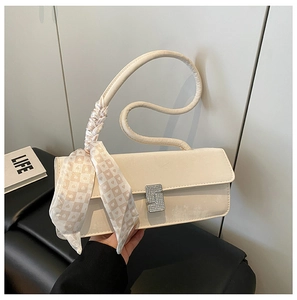 Close-up of cream square shoulder bag featuring rhinestone buckle and heart pattern silk scarf