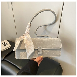 Detail of silver shoulder bag featuring rhinestone buckle and scarf-wrapped handle