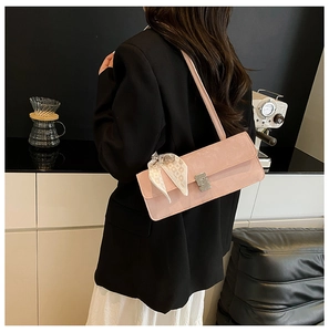 Detailed close-up of a pink suede shoulder bag with an elegant floral silk scarf detail