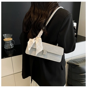 Detail of grey baguette bag featuring a crystal buckle and silk scarf strap detail