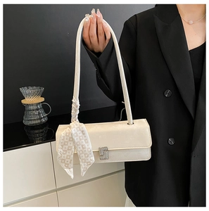 Detail of a creamy white leather underarm bag with diamond buckle and silk scarf accent