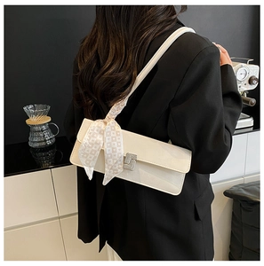 Beige faux leather shoulder bag with decorative silk scarf on model in black blazer