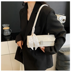 Close-up of white baguette bag with rhinestone buckle and silk scarf detail