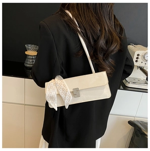 Detail of cream shoulder bag with crystal buckle and elegant silk scarf decoration