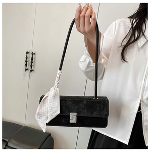 Detail of black velvet shoulder bag with silver rhinestone buckle and silk scarf strap
