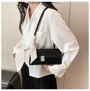 Detail of black shoulder bag with silver rhinestone buckle and patterned silk scarf accent