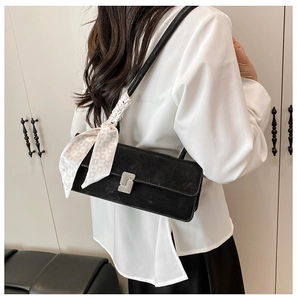 Detail of a black suede shoulder bag featuring a silver S-buckle and silk scarf handle