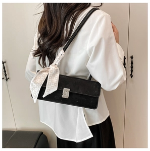 Detail of black suede shoulder bag with silver S-buckle and heart scarf on model