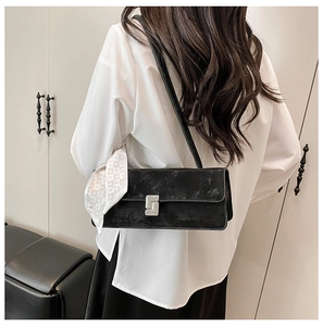 Close-up of black shoulder bag with silver rhinestone buckle and plaid silk scarf decoration