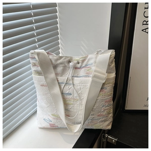 Dettaglio della borsa tote in tela bianca con motivi a onde colorate e tracolla larga