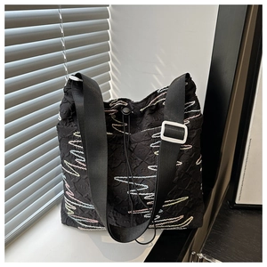 Dettaglio borsa tote nera trapuntata con ricami colorati e tracolla larga in nylon