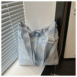 Dettaglio borsa tote in nylon increspato azzurro con ricami a onde colorate e coulisse