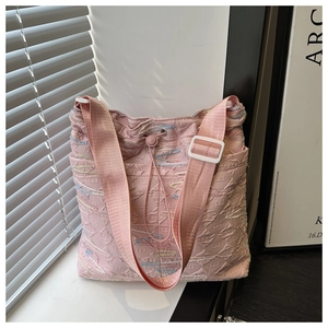 Dettaglio della borsa a secchiello rosa con logo a rilievo e ricami ondulati colorati