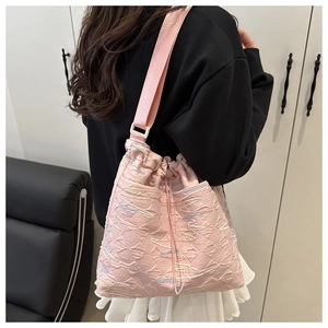 Dettaglio borsa tote rosa con texture in rilievo e ricamo a onde su tracolla larga