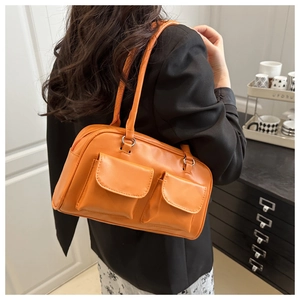 Detail showing an orange shiny shoulder bag with double pockets and vintage style