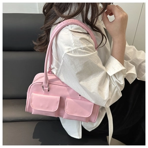 Detailed view of pink glossy underarm bag featuring dual front pockets and shoulder strap