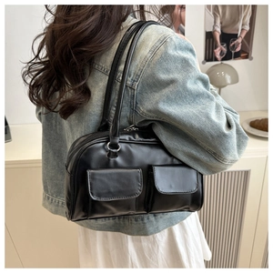 Close-up of a black glossy shoulder bag with dual front pockets and sleek leather texture