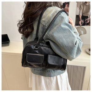 Detail showing two front flap pockets on a black PU leather tote bag with long straps