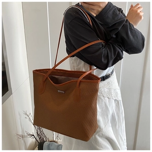 Close-up of brown woven tote bag showing fine texture and metallic logo detail