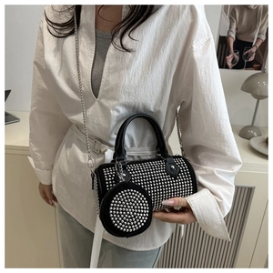 Détail du sac cylindrique noir à rivets avec chaîne argentée et pochette sur le mannequin
